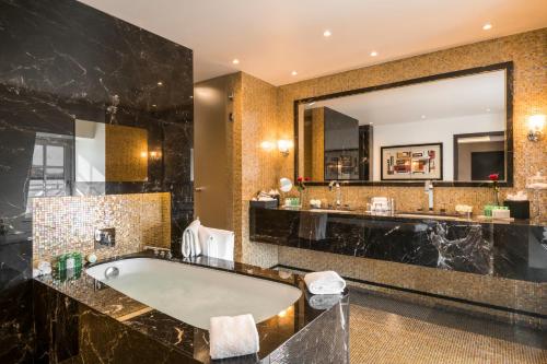 a bathroom with a tub and a large mirror at Warwick Brussels - Grand Place in Brussels