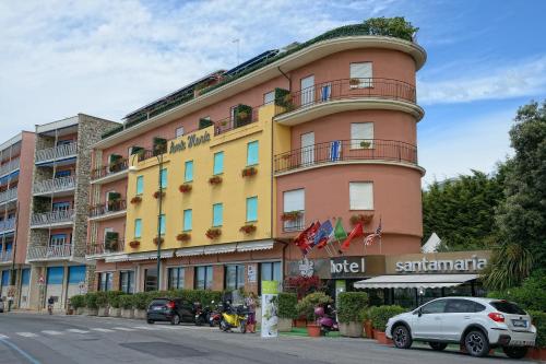 a large pink and yellow building with cars parked in front of it at Hotel Santa Maria in Chiavari