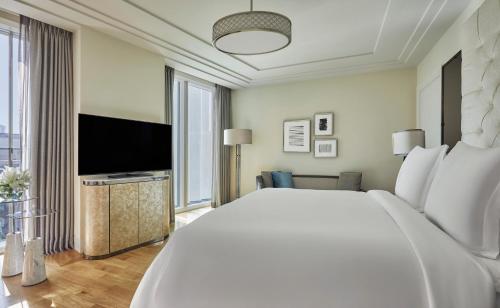 a bedroom with a large bed and a flat screen tv at Four Seasons Hotel Abu Dhabi at Al Maryah Island in Abu Dhabi