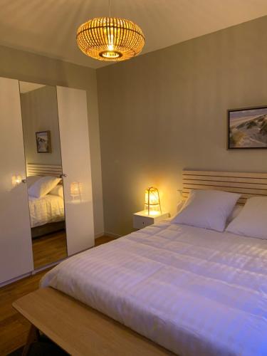 - une chambre avec un grand lit blanc et un lustre dans l'établissement Appartement de 95 m2 bien situé, à Boulogne-sur-Mer