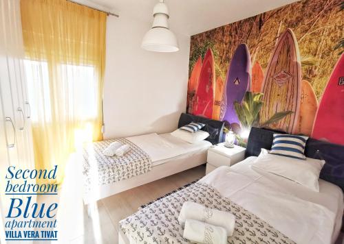 two beds in a room with surfboards on the wall at Apartments Villa Vera in Tivat
