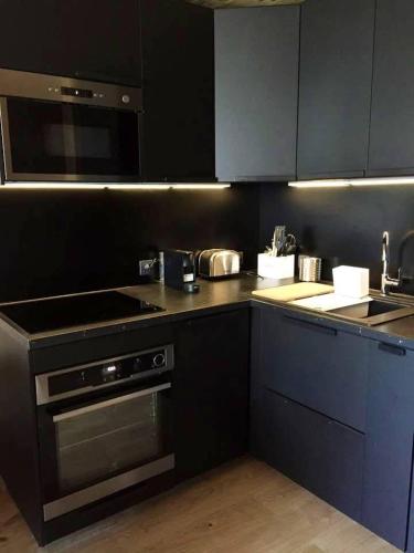 une cuisine avec des armoires noires et un four à plaques de cuisson dans l'établissement Alpe d'Huez Le Majestic 2 skis aux pied, à L'Alpe-d'Huez