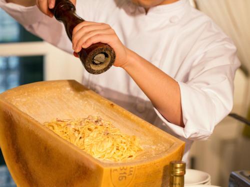 a woman is preparing noodles in a wooden container at Hotel Monterey Osaka in Osaka