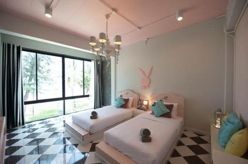 a bedroom with two beds and a large window at De Sea Almond in Chumphon