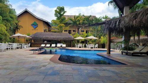 a pool at a resort with chairs and umbrellas at FLAT ILHA FLAT HOTEL in Ilhabela