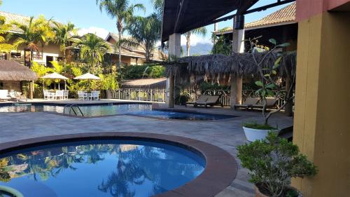 uma piscina ao lado de um edifício com um resort em FLAT ILHA FLAT HOTEL em Ilhabela