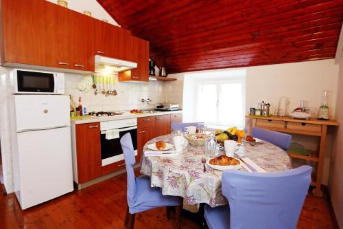 a kitchen with a table with blue chairs and a white refrigerator at Apartment Dulcis in Stari Grad