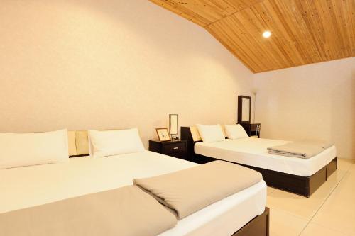 1 dormitorio con 2 camas y techo de madera en Homeinn, en Meinong
