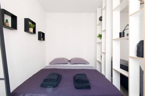 - une chambre avec un lit doté de draps et d'étagères violets dans l'établissement Le Temple de La Rochelle, à La Rochelle