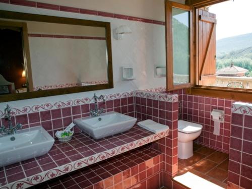 a bathroom with two sinks and a toilet and a mirror at Hotel La Parra in Aliaga