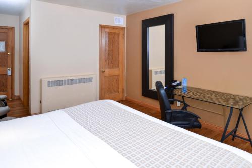 a bedroom with a bed and a desk and a television at Valued Stay Mayflower in Madison
