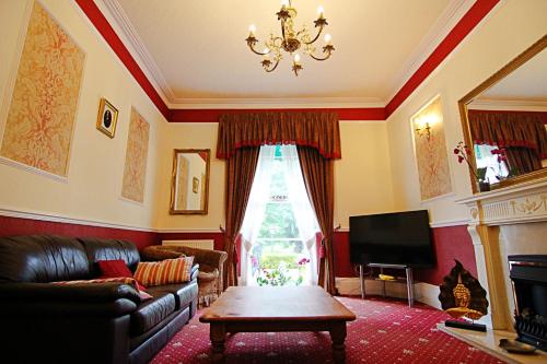 a living room with a couch and a table and a television at The Daylesford Guest House in Torquay