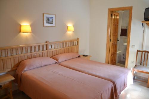 a bedroom with two beds and two lights on the wall at Hostal Los Claveles in Priego