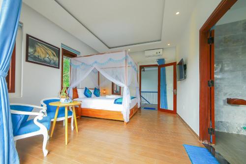 a bedroom with a canopy bed and a table and chairs at Hoi An Sea Village Homestay in Hoi An