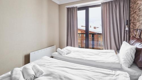 two white beds in a room with a window at Gudauri Loft Hotel in Gudauri