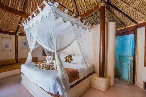 a bedroom with a bed with a canopy at Sanghyang Bay Villas in Nusa Lembongan