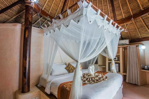
a large bed with a canopy on top of it at Sanghyang Bay Villas in Nusa Lembongan
