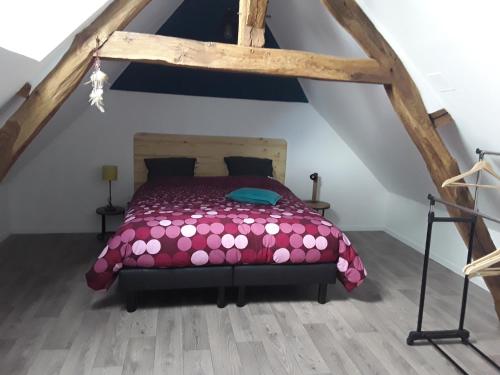 ein Schlafzimmer mit einem rosa Bett im Dachgeschoss in der Unterkunft Le Gros Tilleul in Chepoix