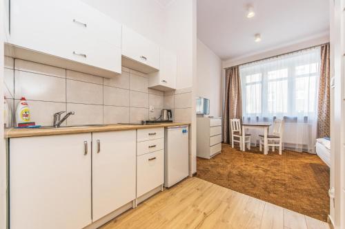 a kitchen with white cabinets and a dining room at Baltic Plaza Gdynia - MAXIMAL in Gdynia