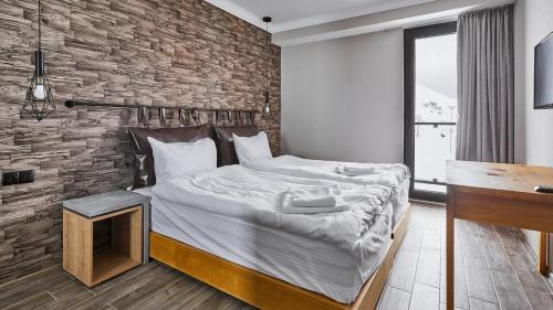 a bedroom with a large bed and a brick wall at Gudauri Loft Hotel in Gudauri
