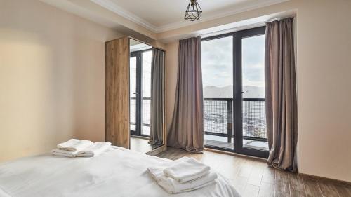 a bedroom with a bed and a large window at Gudauri Loft Hotel in Gudauri