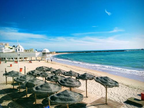 un gruppo di ombrelloni su una spiaggia con l'oceano di Los Patios de la Caleta a Cadice