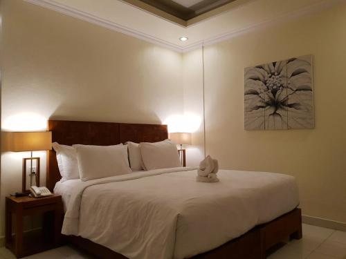 a bedroom with a bed with two lamps and a painting at Hotel Genggong in Candidasa