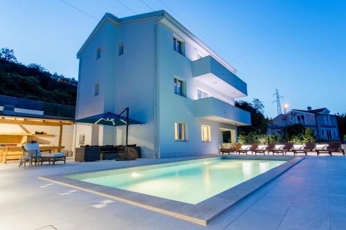 eine Villa mit einem Pool vor einem Gebäude in der Unterkunft Villa Marta in Opatija