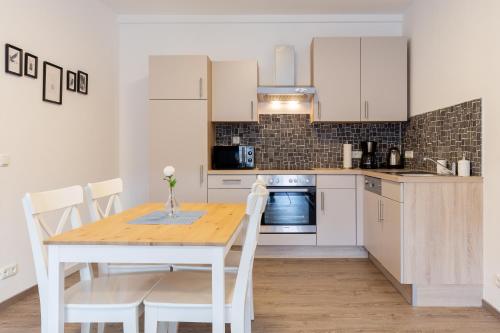 Una cocina con una mesa de madera y gabinetes blancos. en atrium untergrafendorf, en Böheimkirchen