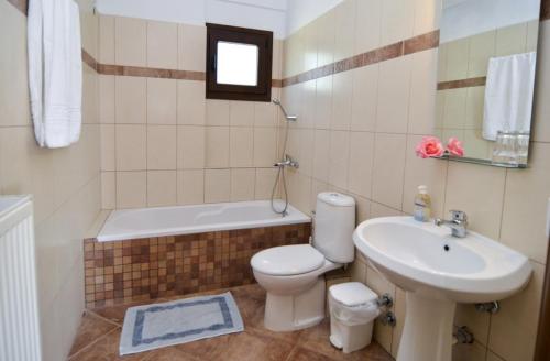 a bathroom with a toilet and a sink and a bath tub at Moonbeam Hotel in Pefkari