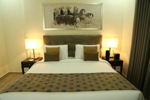 a bedroom with a large bed with two lamps at Uptown Hotel Apartment Fujairah By Gewan in Fujairah