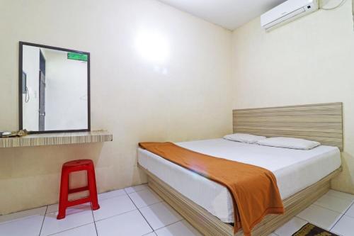 a bedroom with a bed and a red stool at Guest House Taman Sari Syariah in Parit