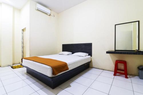 a bedroom with a bed with a mirror and a red stool at Guest House Taman Sari Syariah in Parit