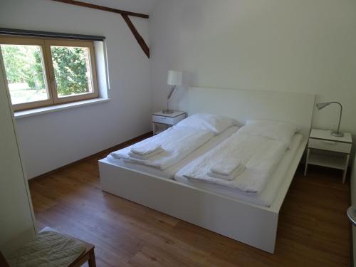 a white bedroom with a bed and a window at Havelhof-Nitzow in Nitzow