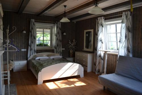 ein Schlafzimmer mit einem Bett, einem Sofa und Fenstern in der Unterkunft Merkiokrantas Pirkia kaime in Puvočiai