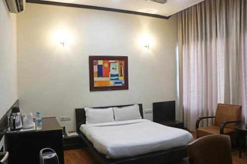 a hotel room with a bed and a desk and chair at Pallavi West in Panchkula