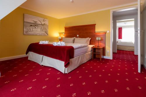 a hotel room with a large bed and red carpet at Pension und Restaurant Gutshaus Kaltenhof in Kaltenhof