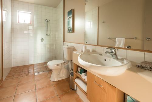 a bathroom with a sink and a toilet and a mirror at Glenfern Villas in Franz Josef