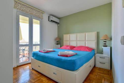 a bedroom with a large bed with blue and red pillows at Lux Apartman Sofia in Sveti Stefan