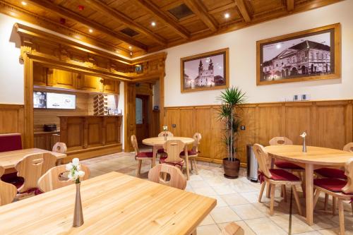 a restaurant with wooden walls and tables and chairs at Pension Kokel in Dumbrăveni