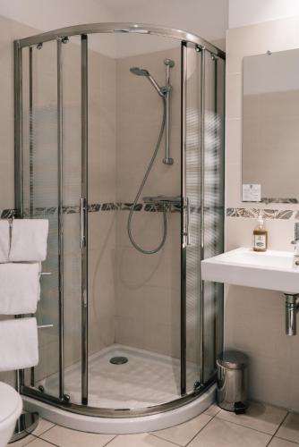 a shower with a glass door in a bathroom at Hôtel La Résidence in Narbonne