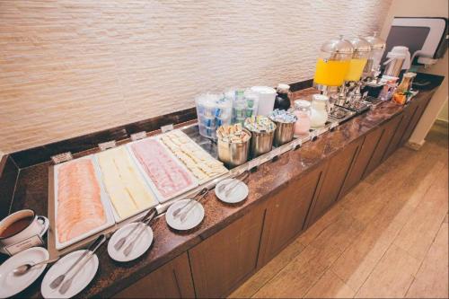 a buffet line with plates and bottles and drinks at Ed Saint Moritz, Flat 02 com Garagem, SHN no Coração de Brasília in Brasilia