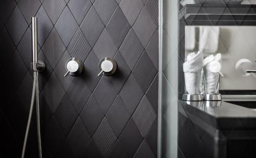 a bathroom with a black tiled wall with a mirror at Tradition Julen Hotel in Zermatt