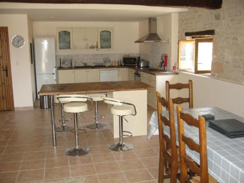 une cuisine avec un comptoir, une table et des chaises dans l'établissement Gite du Puits - Bréville, à Bréville
