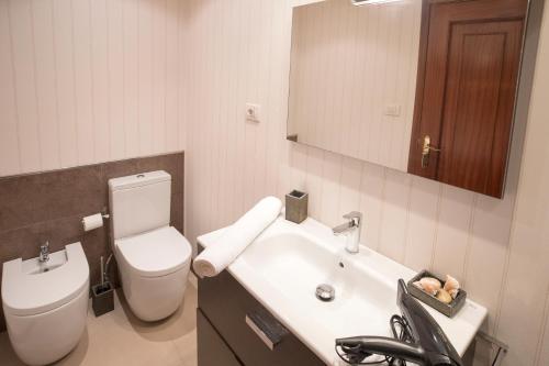 Un baño con lavabo, inodoro y espejo. en JacobeAndo, en Sarria