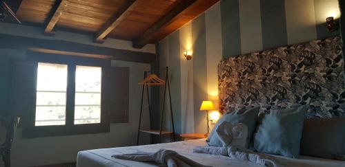 a bedroom with a large bed with a window at Hotel Judería Valle del Jerte in Cabezuela del Valle