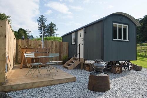 a black tiny house with a wooden deck at West Coast Hideaways in Nedd