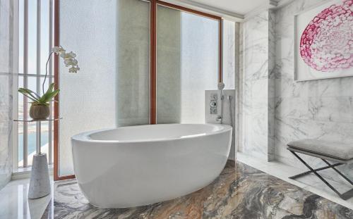 a white bath tub in a bathroom with a chair at Four Seasons Hotel Abu Dhabi at Al Maryah Island in Abu Dhabi