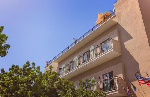 a man is standing on the balcony of a building at Kalvin Boutique Hotel by Levinsky Market Tel-Aviv in Tel Aviv