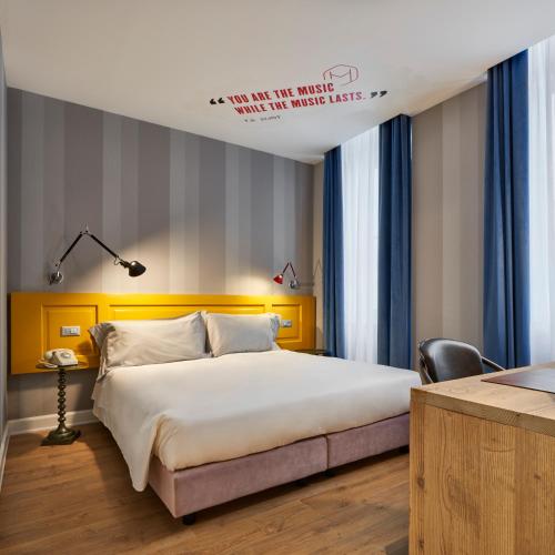 a bedroom with a large bed with a yellow headboard at The Modernist Hotel in Trieste